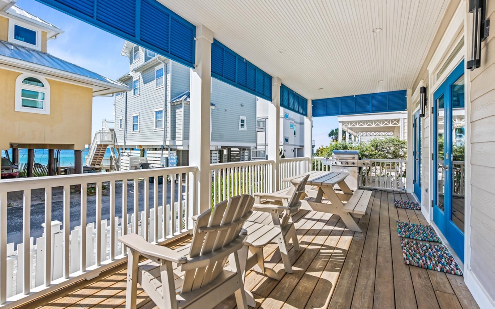 Your private covered deck with coastal charm—perfect for morning coffee at the picnic table or afternoon relaxation in comfortable Adirondack chairs.
