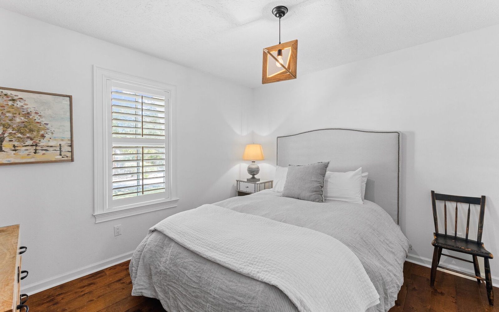 Drift off in this serene bedroom where soft gray linens and warm wood floors create your perfect retreat for peaceful nights.