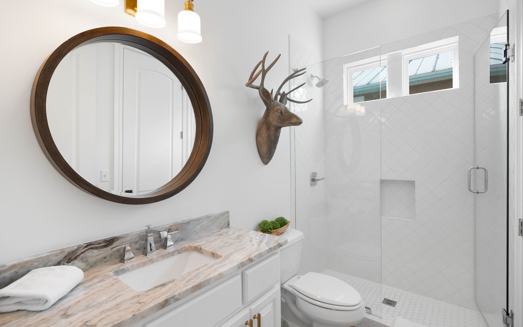 Refresh in your stylish bathroom featuring marble countertops, a spacious glass shower, and charming rustic touches.
