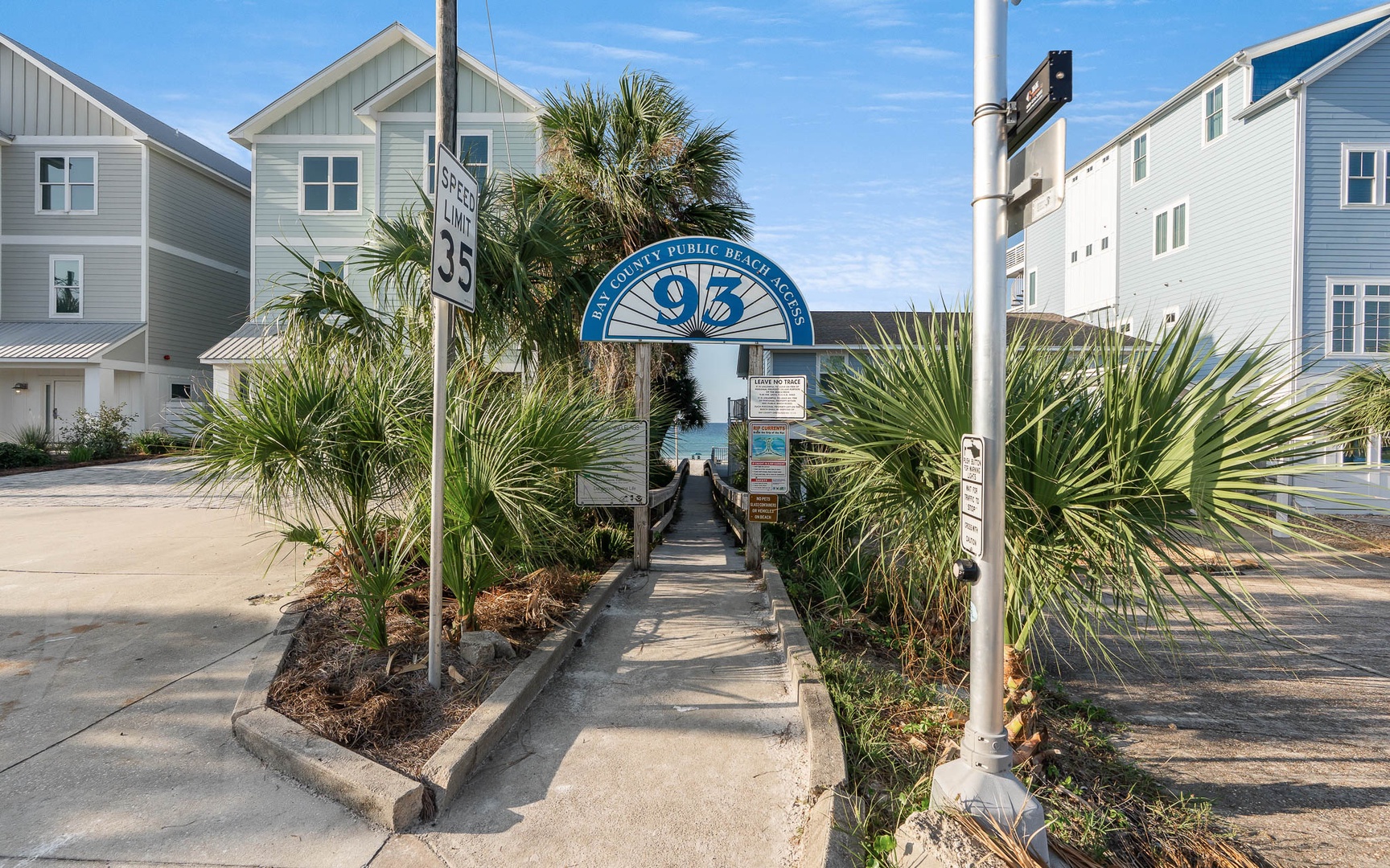 Public beach access walkway surrounded by coastal homes and tropical landscaping in this charming seaside neighborhood.