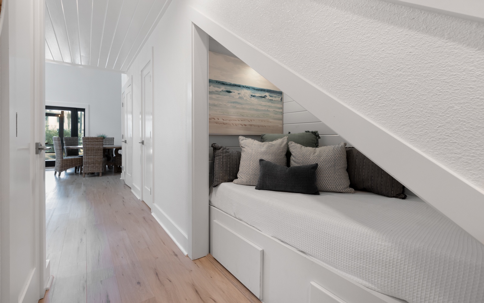 Cozy reading nook tucked beneath your stairs offers tranquil ocean views with plush cushions for lazy afternoons.