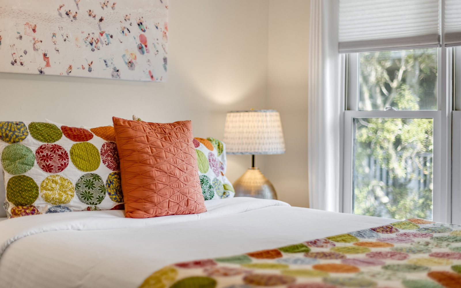 Sink into this cheerfully decorated bedroom with colorful pillows, soft lighting, and leafy garden views through your window.