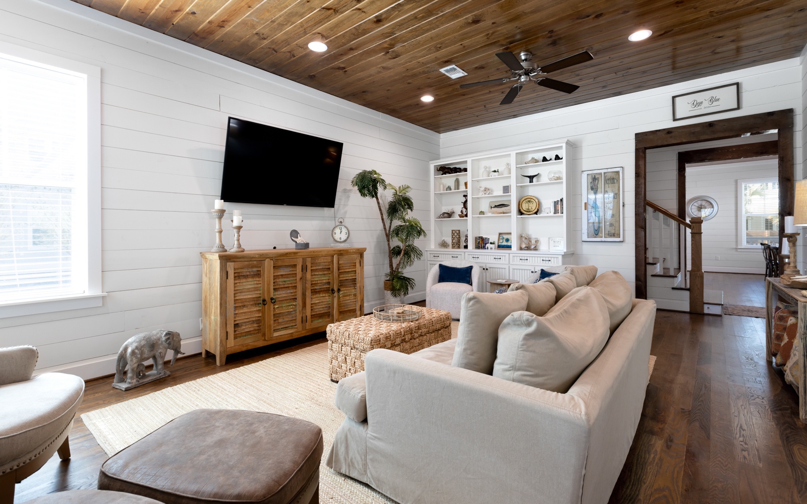Sink into the plush sectional sofa and enjoy movie nights on the large TV in this stylish living room with rustic wood ceiling.