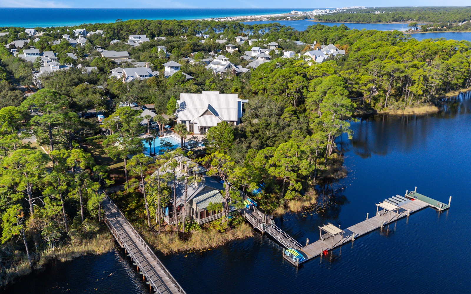 Aerial view of waterfront property nestled among lush trees with private dock extending into pristine lake waters.