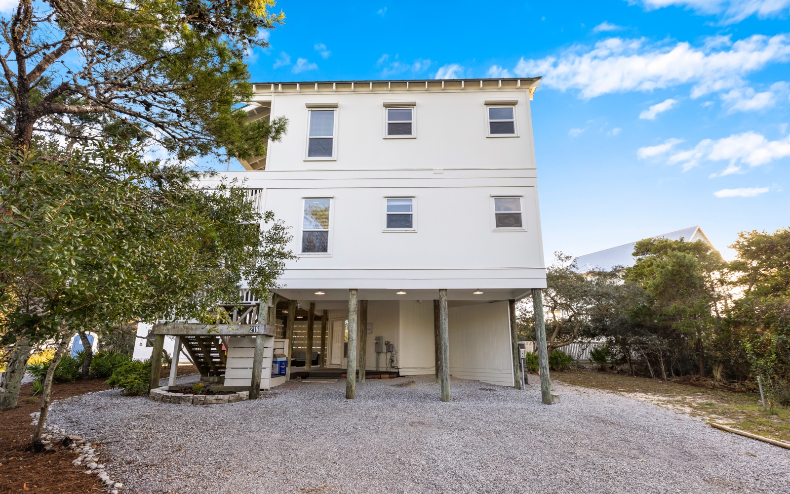 This elevated beach house offers a welcoming arrival with covered parking and coastal charm in a peaceful setting.