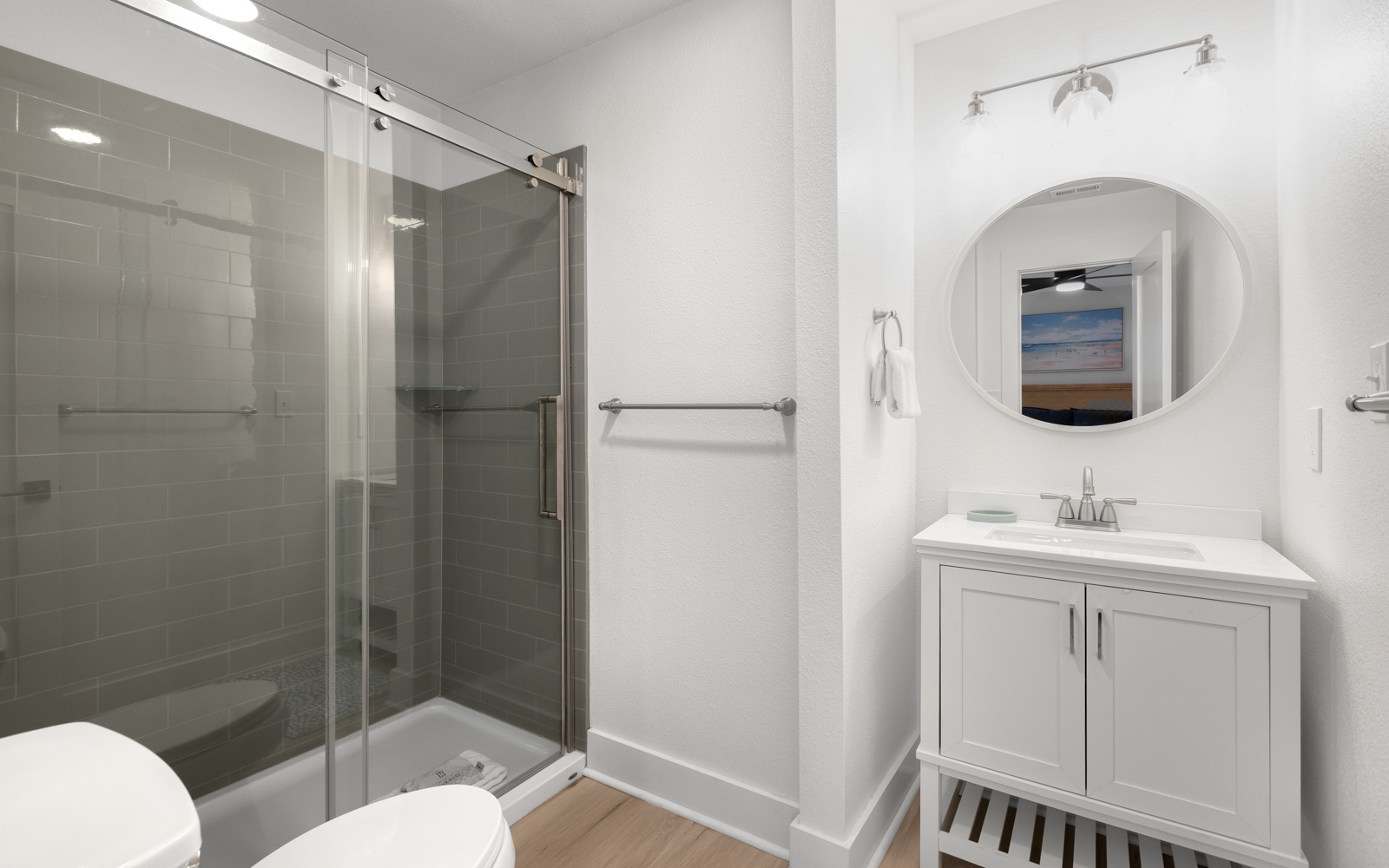 Your private bathroom features a spacious glass shower, elegant vanity, and coastal artwork that creates a spa-like retreat.