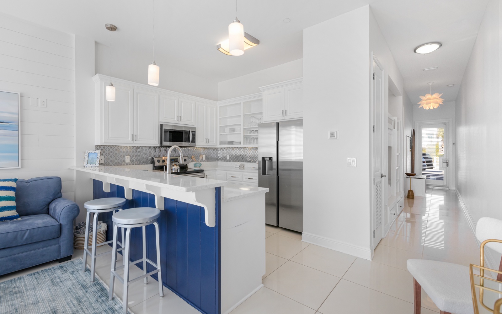 Your fully-equipped kitchen with sleek white cabinets and vibrant blue island awaits your culinary adventures.