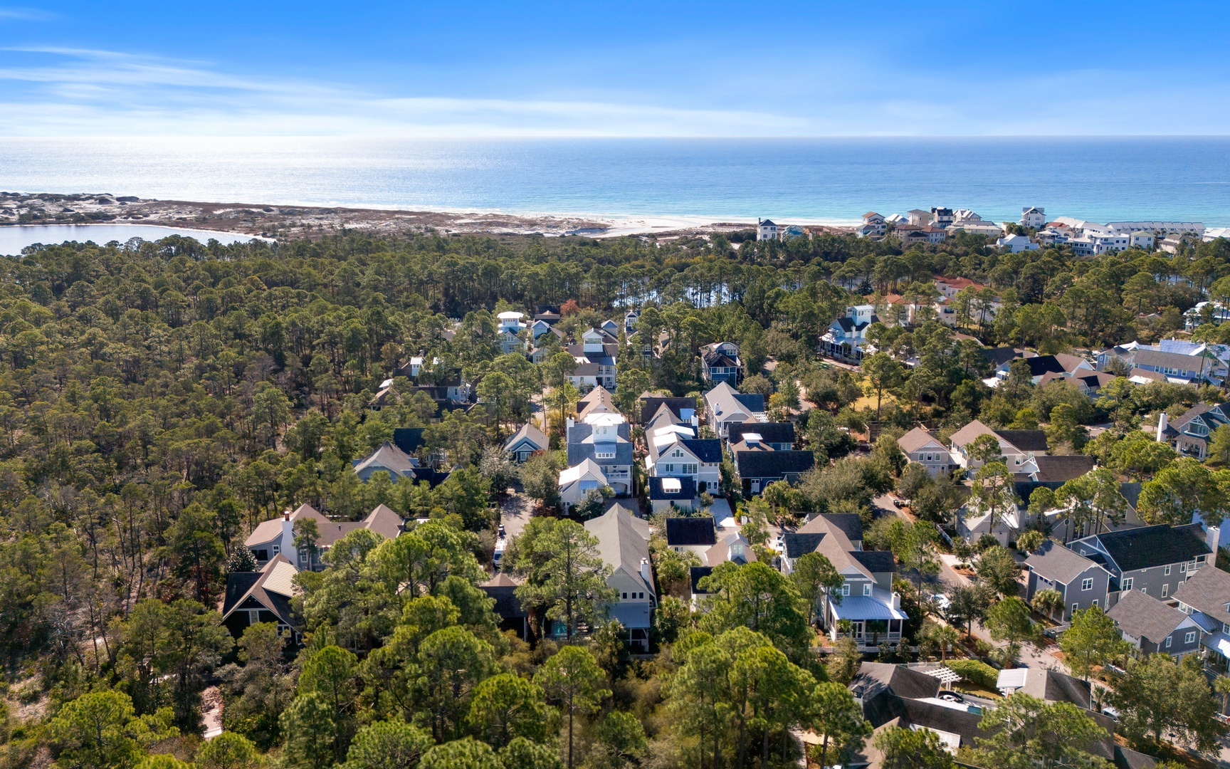 Coastal community nestled among lush trees with pristine beaches and turquoise waters visible in the distance.