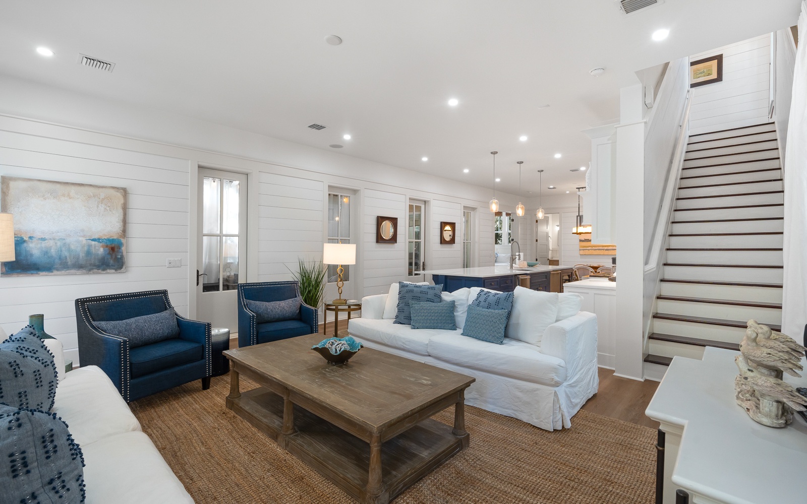 Unwind in your bright coastal living room with plush seating, whitewashed walls, and an open layout that flows seamlessly into the kitchen.