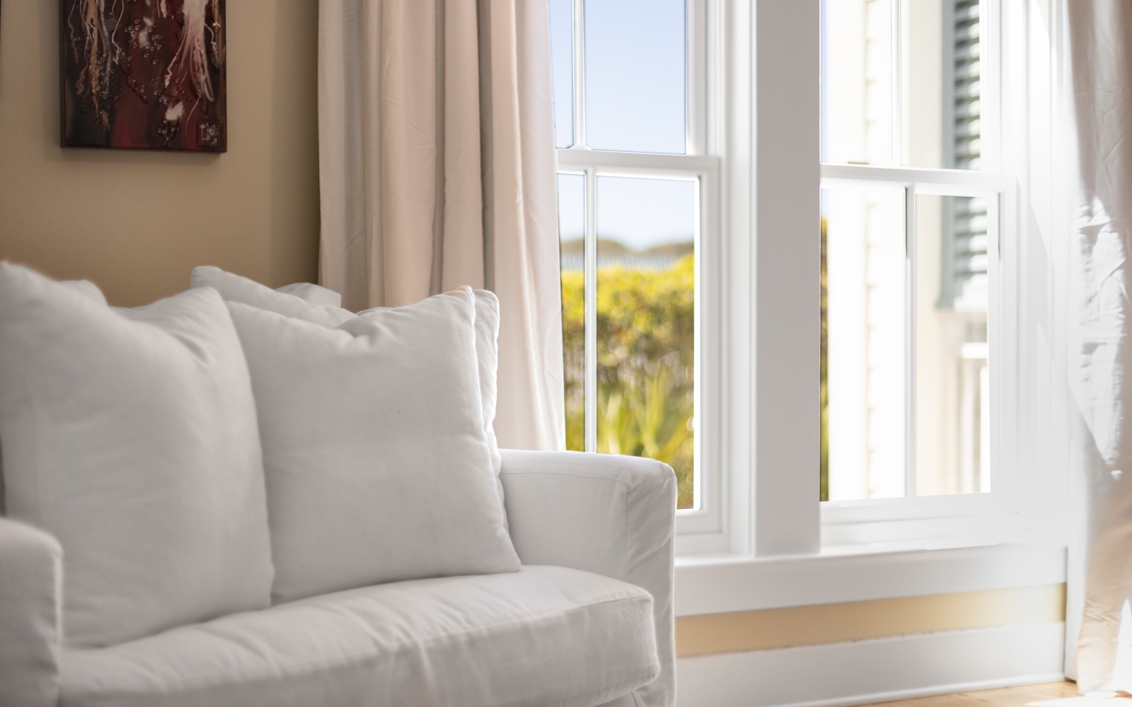 Sink into plush white cushions as gentle sunlight filters through your window, creating the perfect spot for morning coffee or afternoon reading.
