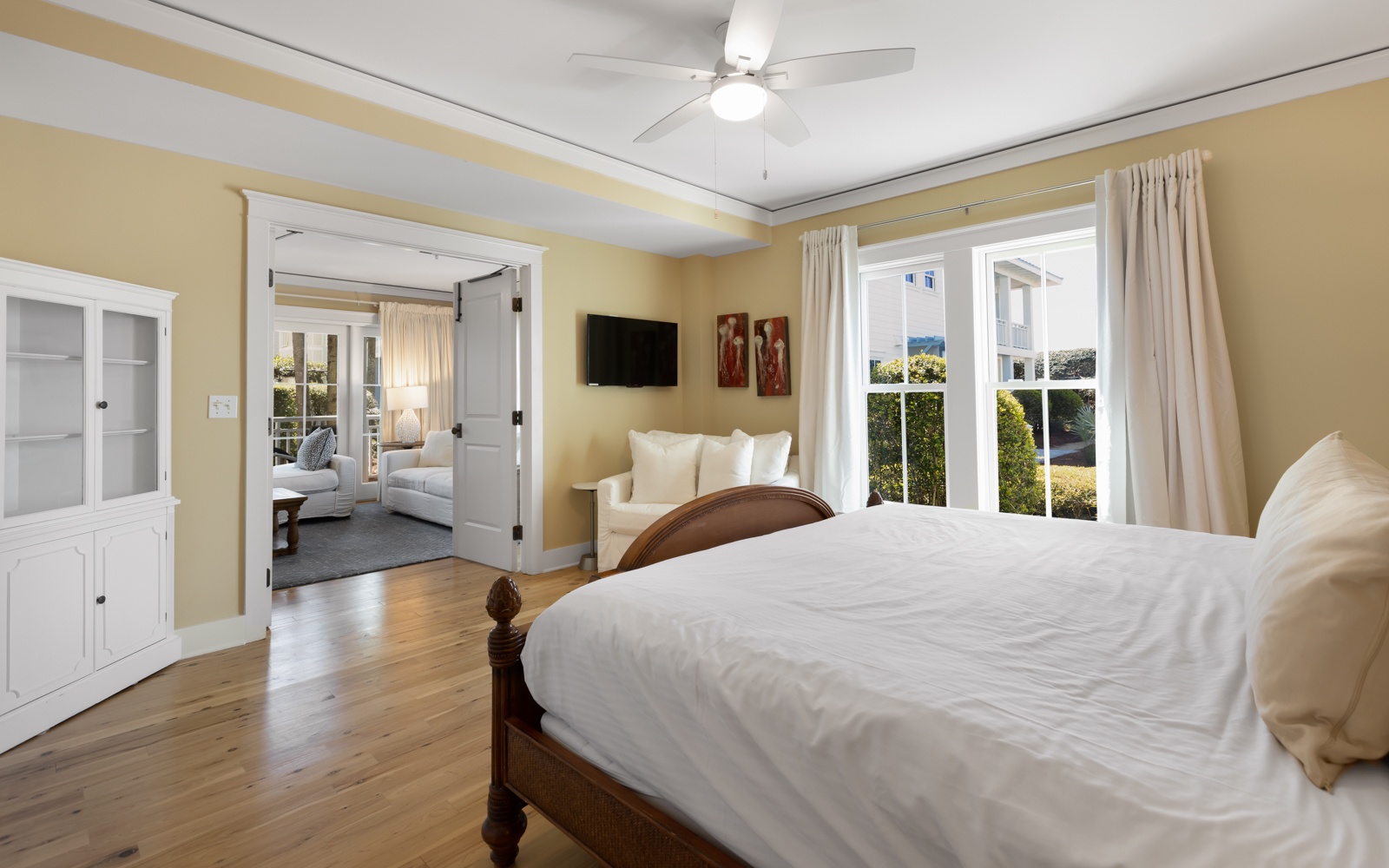 Drift into peaceful sleep in your spacious bedroom, where soft morning light filters through French doors and a gentle ceiling fan keeps you cool.