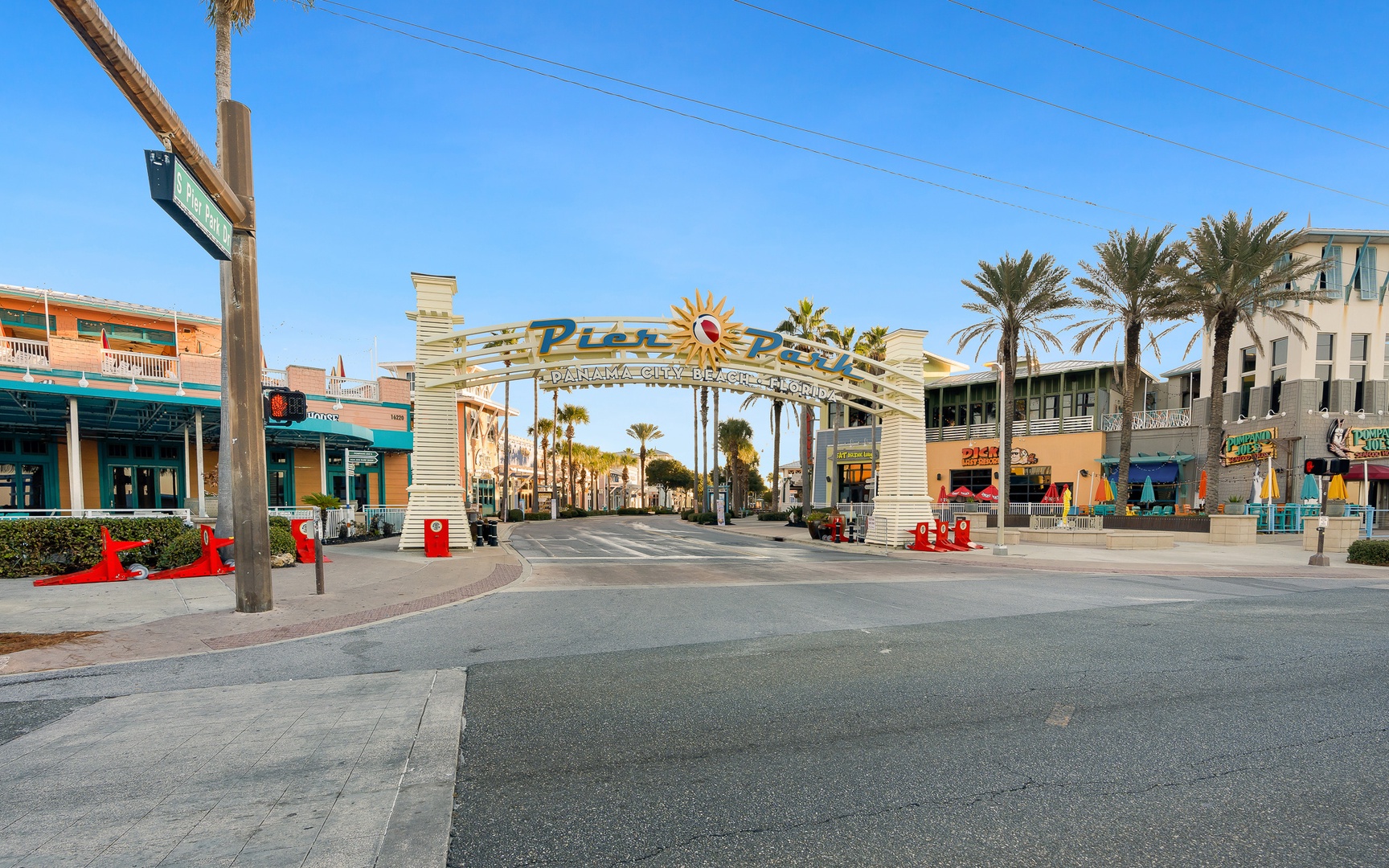 Welcome arch entrance to Panama City Beach's pier district featuring shops, restaurants, and palm-lined streets in sunny Florida.