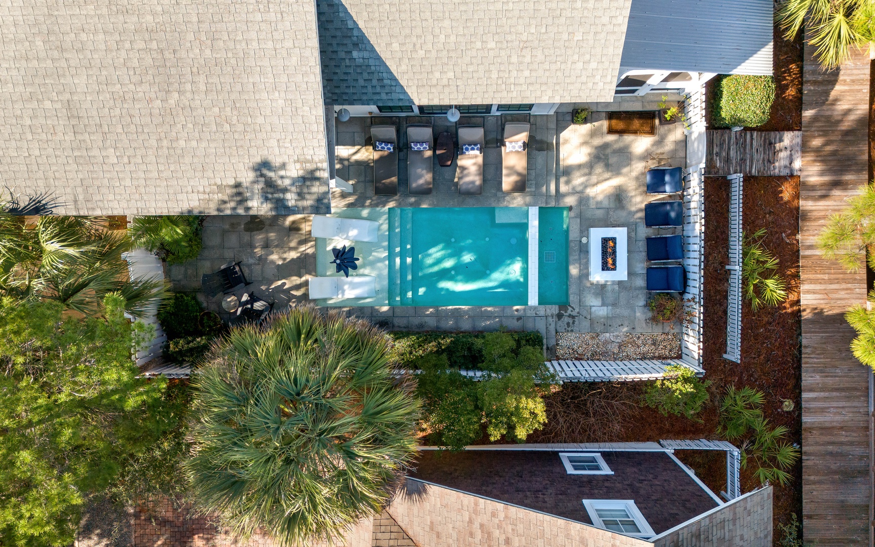 Aerial view of a luxury villa showcasing a pristine swimming pool surrounded by tropical landscaping and contemporary outdoor design.