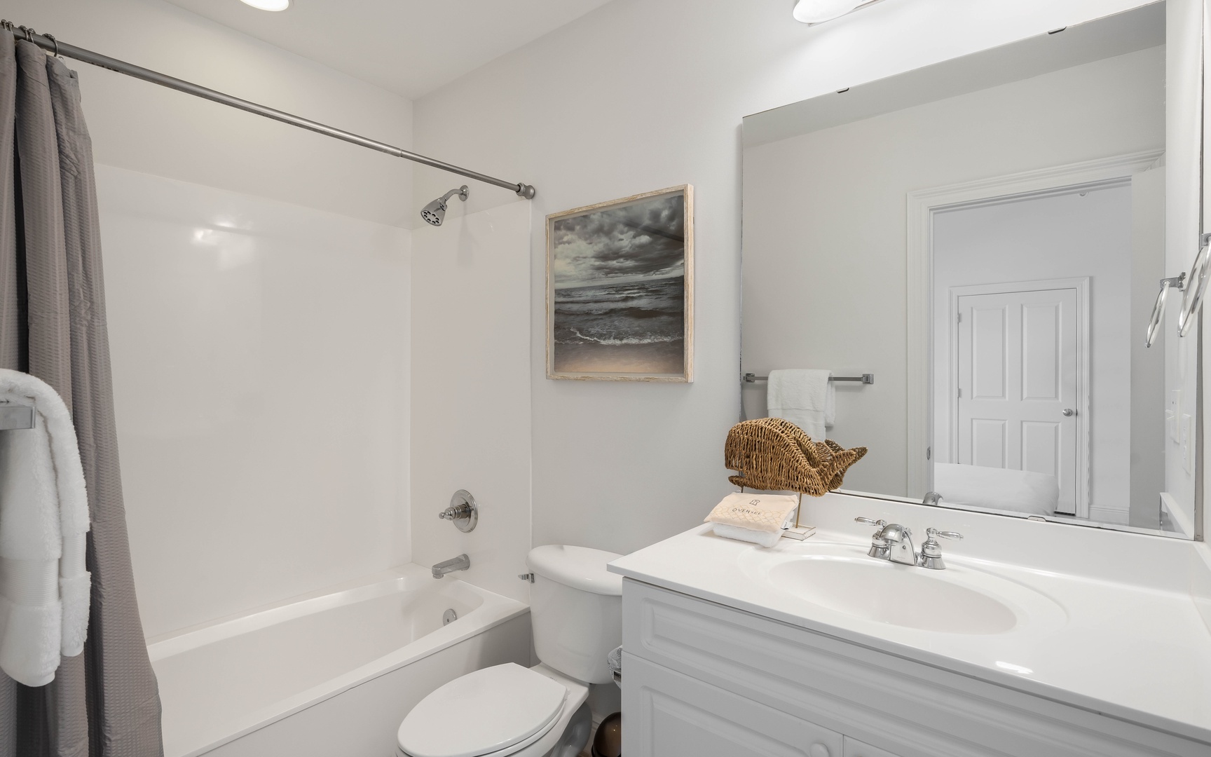 Refresh in your pristine bathroom with a relaxing tub, coastal artwork, and fluffy towels waiting for you.