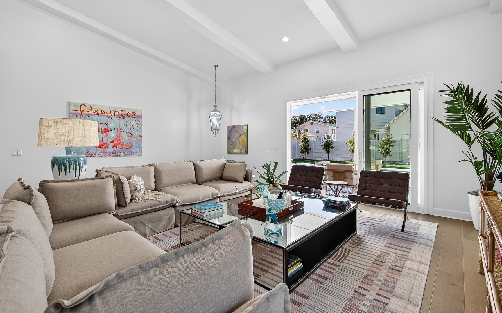 Sink into plush sofas beneath soaring beam ceilings in your bright, modern living space with floor-to-ceiling windows.