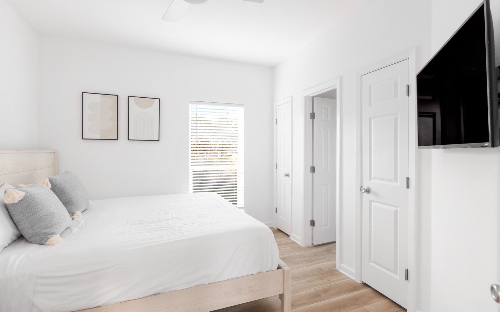 Your serene bedroom features crisp white linens, warm wood floors, and a mounted TV for cozy nights in.