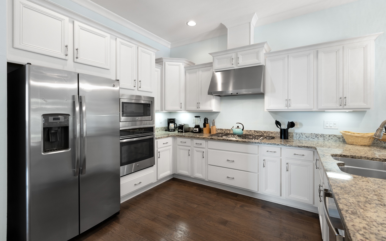 Your fully-equipped kitchen features gleaming granite counters, stainless steel appliances, and pristine white cabinetry—perfect for preparing memorable meals during your stay.