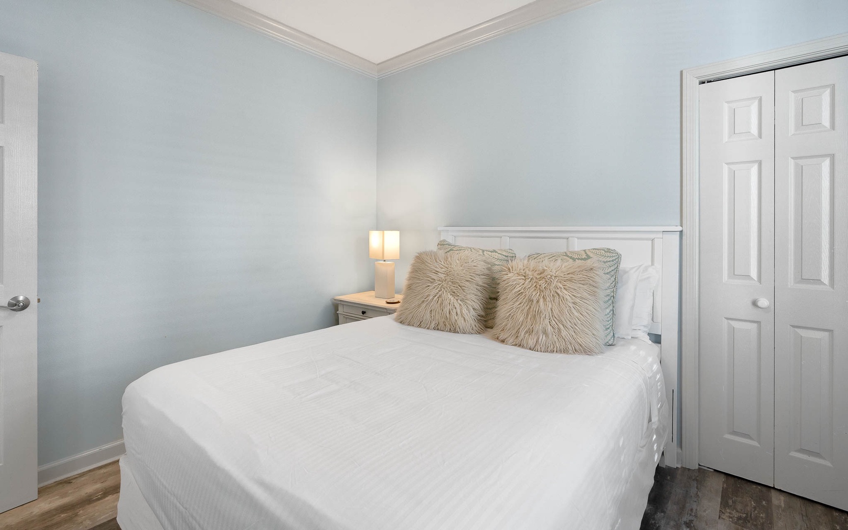 Sink into crisp white linens and fluffy pillows in your serene bedroom retreat, where soft lighting creates the perfect ambiance for rest.