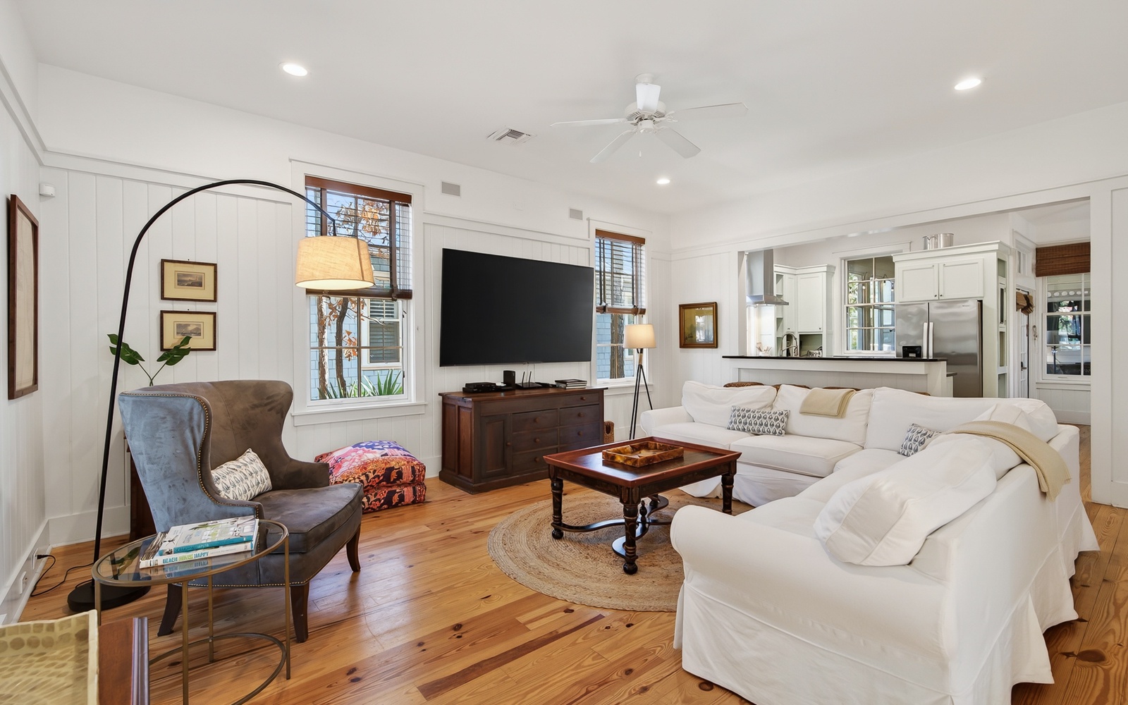 Sink into the plush white sectional sofa and unwind in this light-filled living space with gleaming hardwood floors and thoughtful touches.