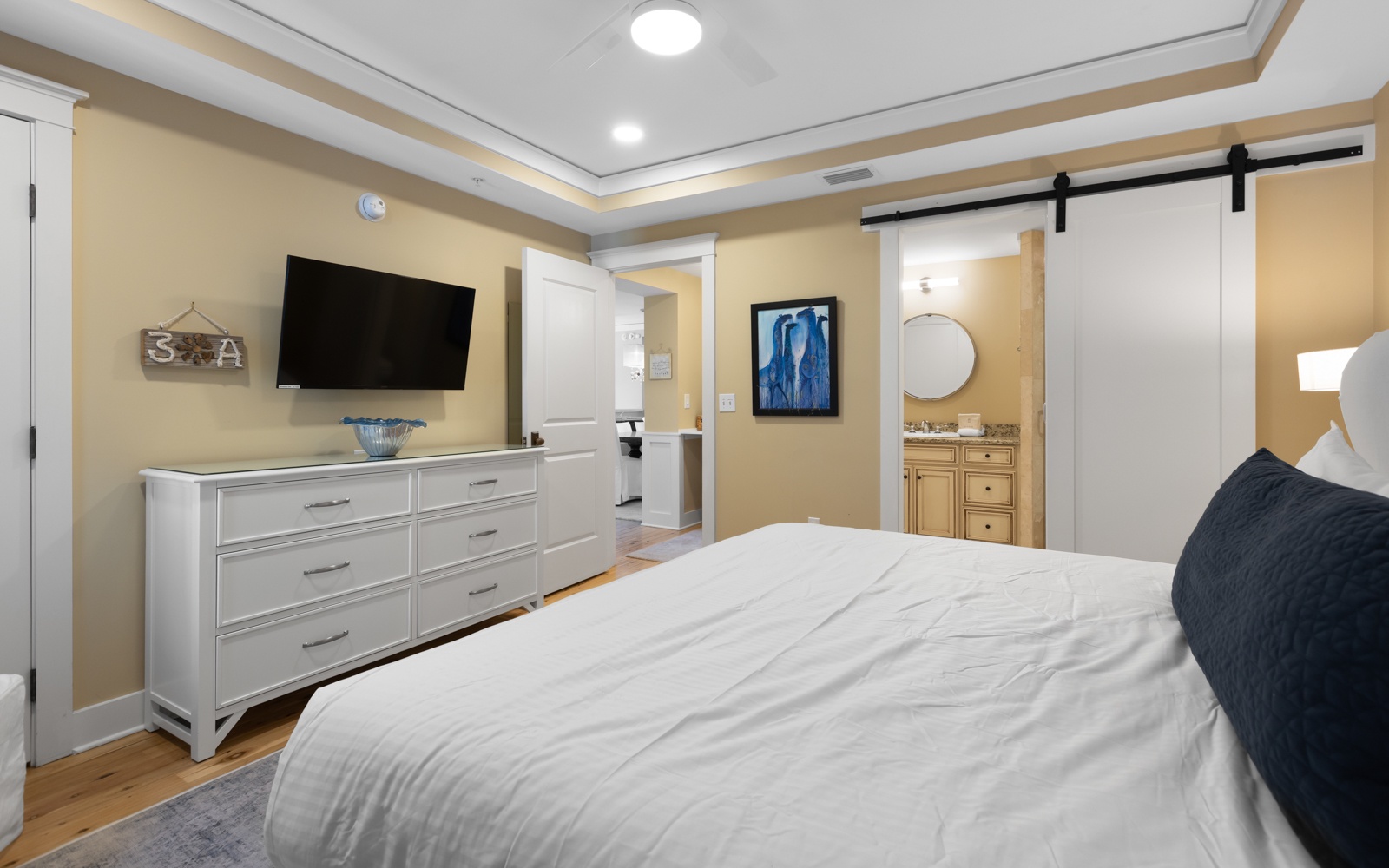 Unwind in your beautifully appointed bedroom featuring a plush bed, modern TV, and elegant sliding barn door bathroom access.