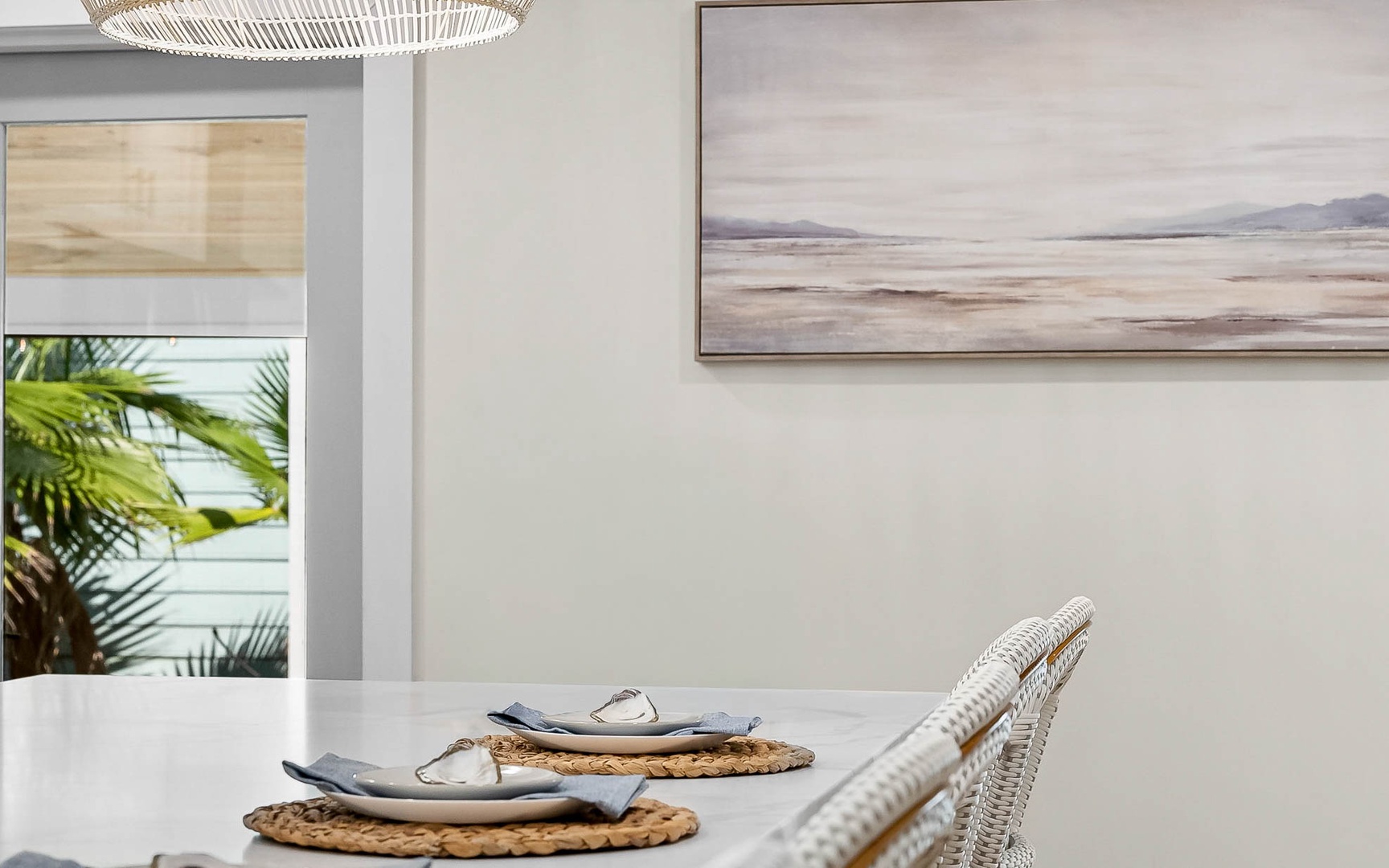 Relax at your elegant dining table with coastal artwork and tropical views just beyond the window.