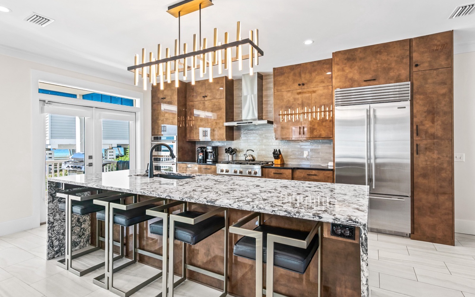 Cook gourmet meals in your stunning kitchen featuring rich wood cabinetry, granite waterfall island, and top-tier stainless appliances.