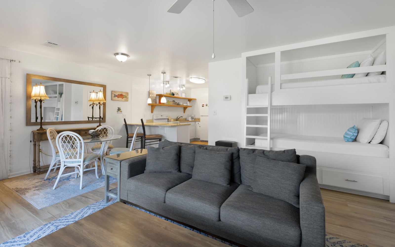 Relax on the plush gray sofa while kids enjoy built-in bunk beds. Open-concept design connects you to the kitchen and dining area.