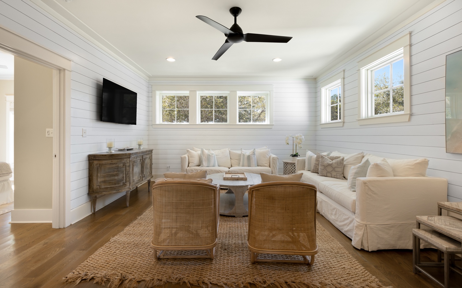 Sink into plush white sofas in this bright living room where shiplap walls and natural light create your perfect retreat space.