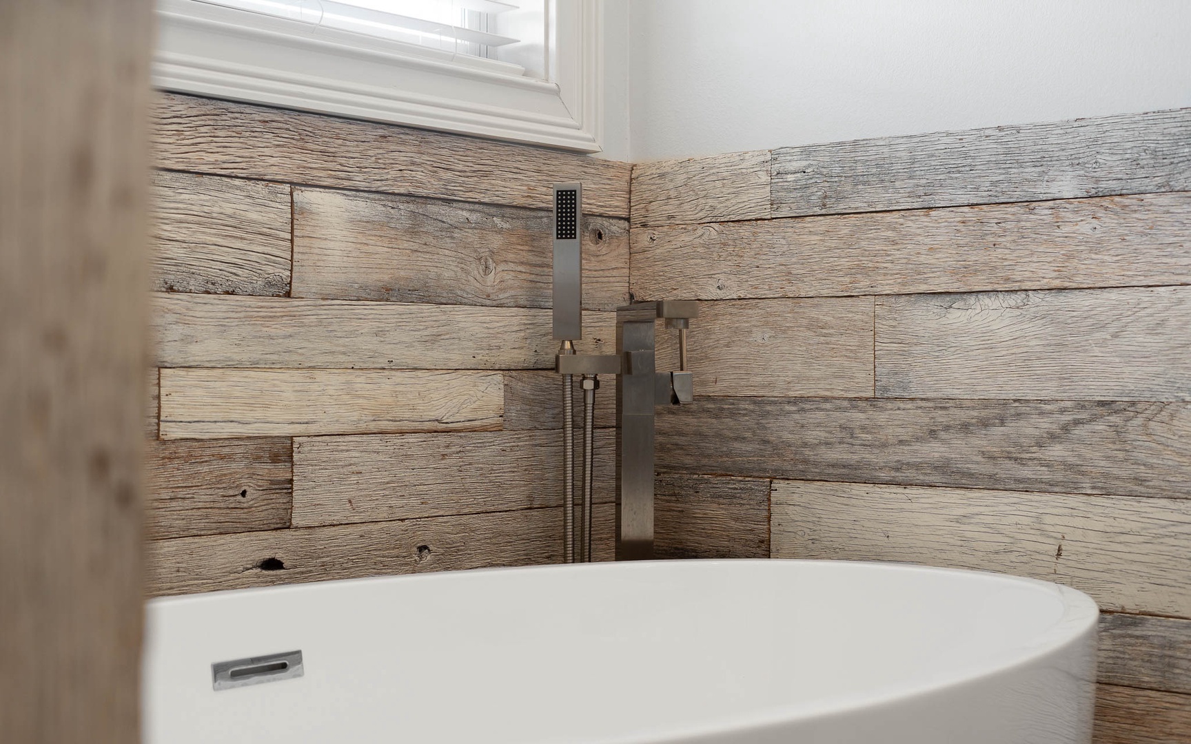 Unwind in your spa-like bathroom featuring a soaking tub surrounded by gorgeous reclaimed wood walls that create the perfect rustic-modern retreat.