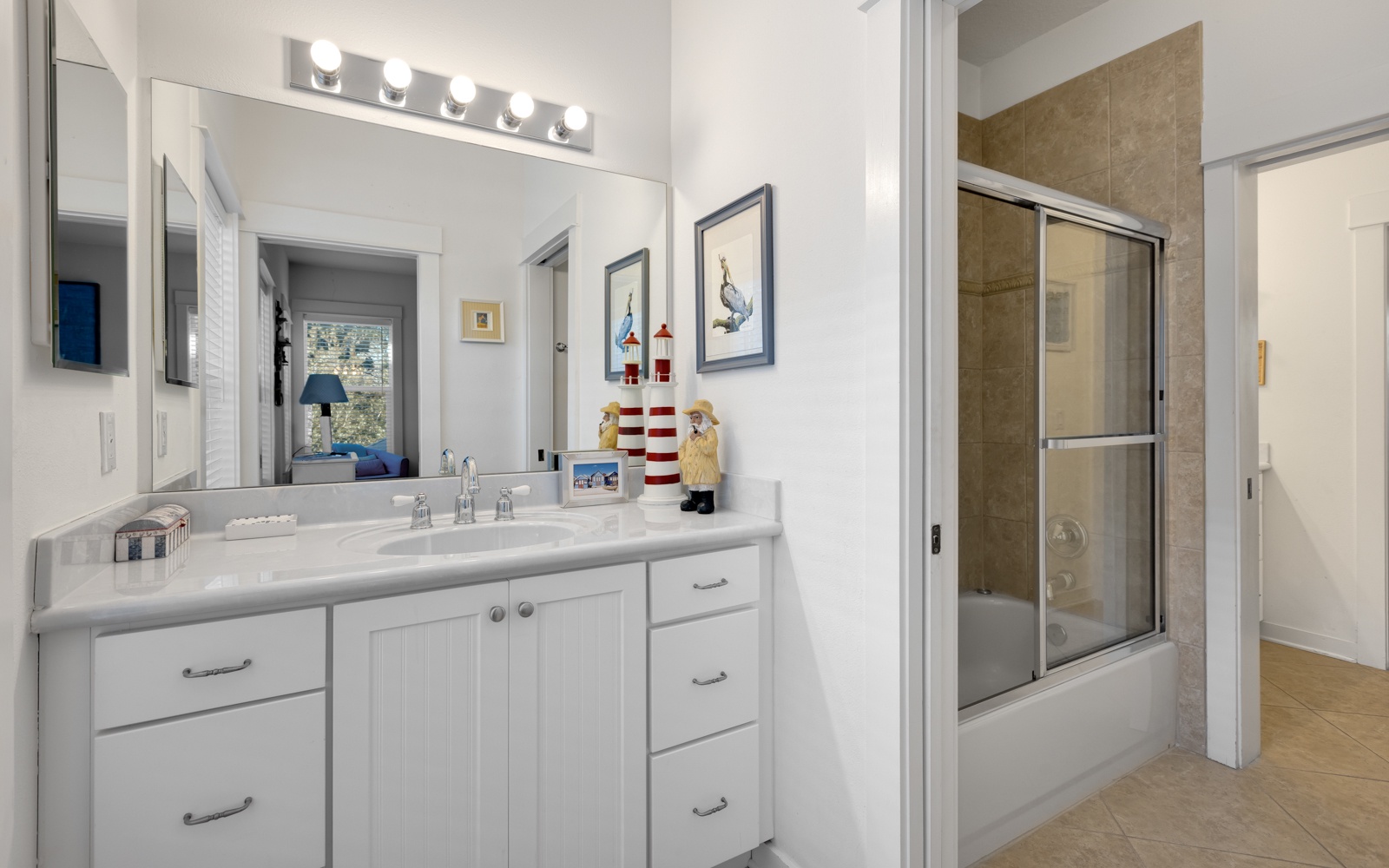 Your spacious bathroom features coastal charm with nautical décor, vanity lighting, and a relaxing shower-tub combo for unwinding after beach days.