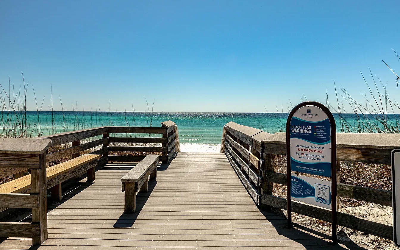 Wooden boardwalk leads to pristine turquoise waters and white sand beach at this coastal location.