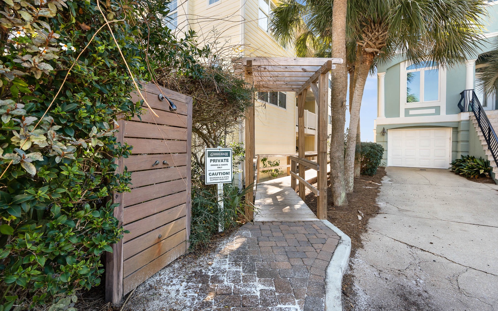Private entrance through tropical landscaping leads to your coastal retreat, featuring palm trees and thoughtful design elements.