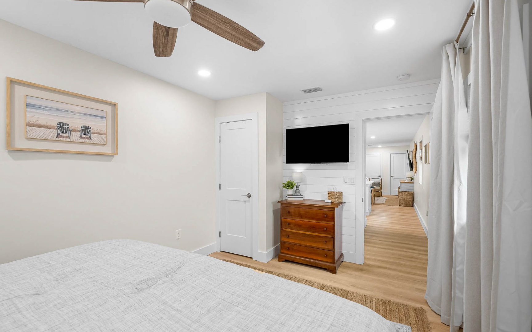Unwind in your peaceful bedroom featuring a ceiling fan, flat-screen TV, and charming coastal artwork that creates the perfect retreat.