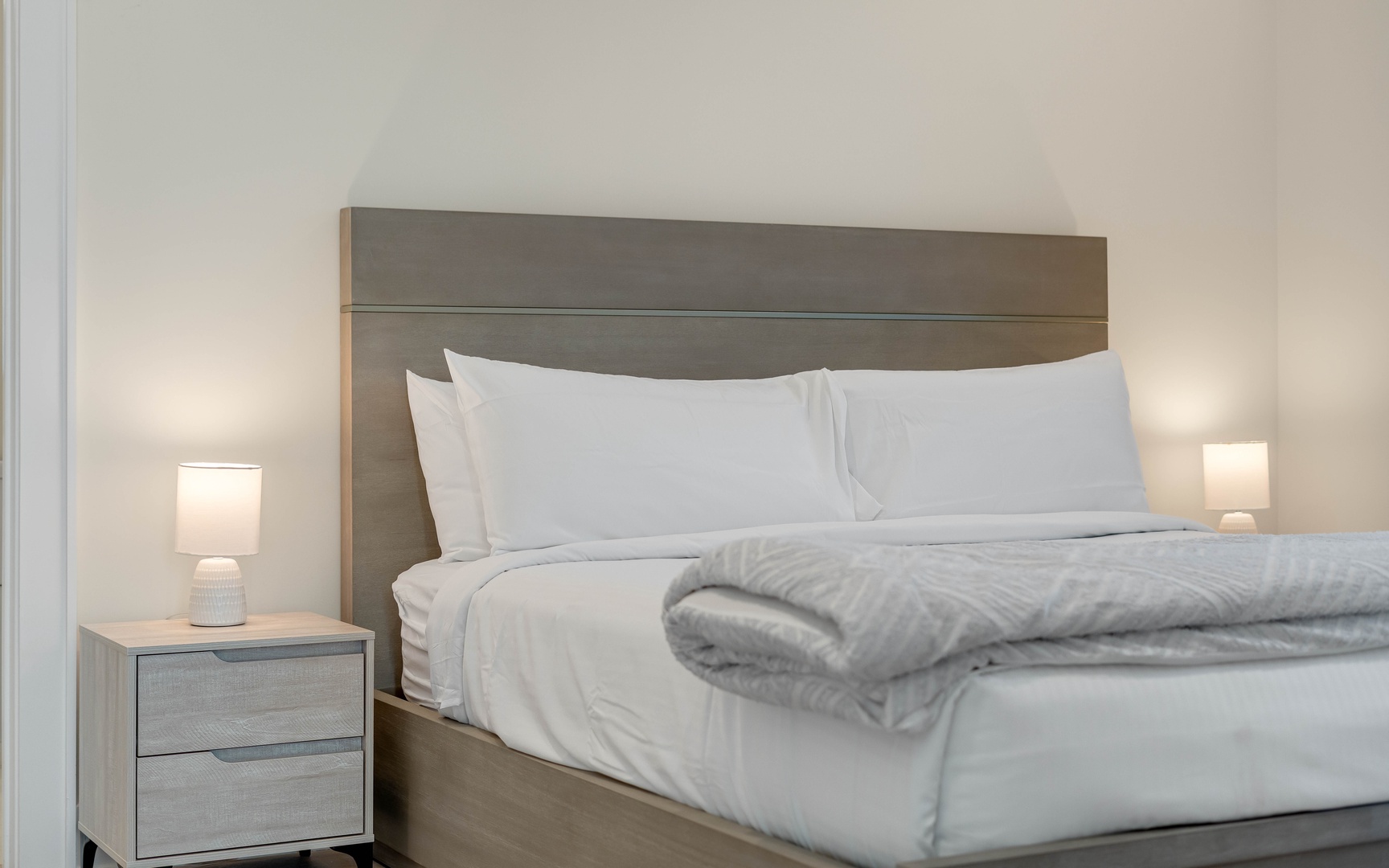 Sink into crisp white linens and plush bedding, where soft lighting creates your perfect retreat for restful nights.