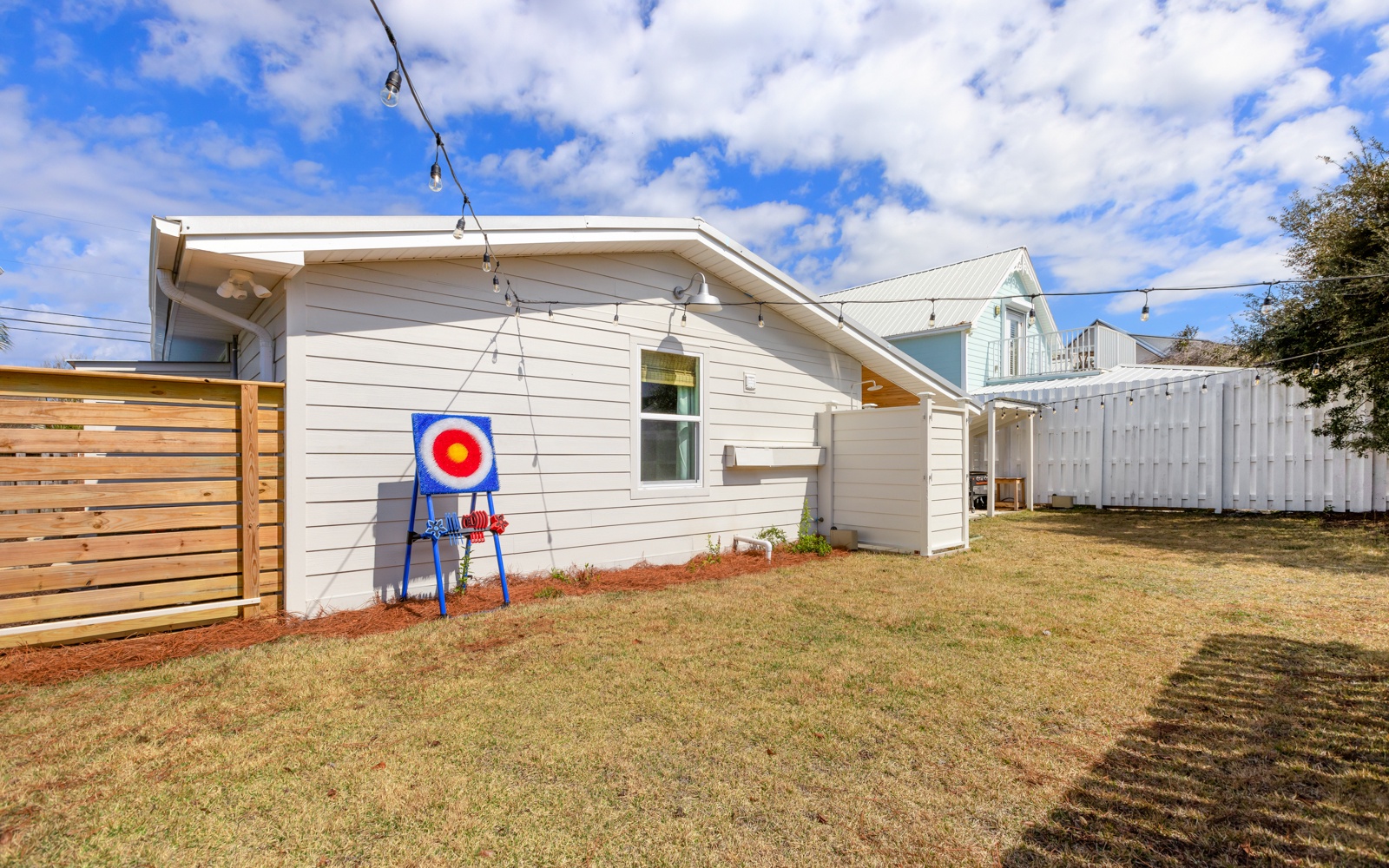 Modern white home features a private fenced backyard with lawn space and children's play equipment in a quiet residential neighborhood.