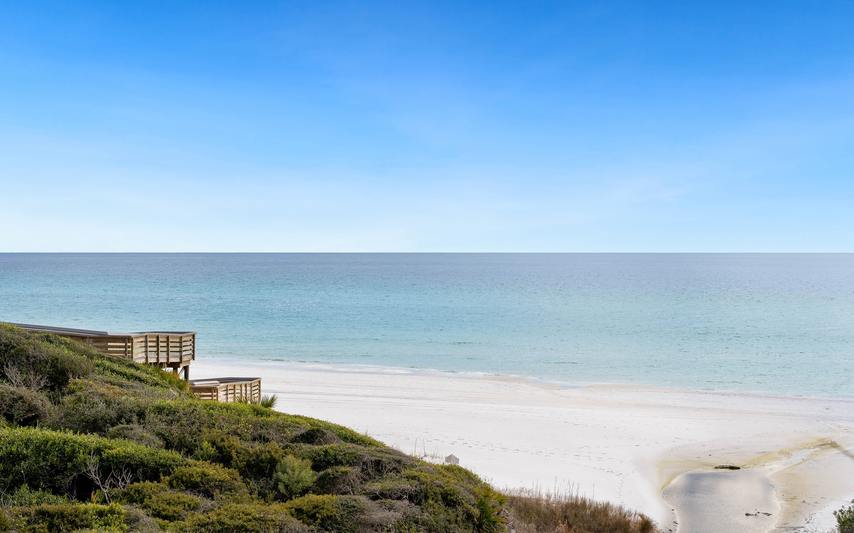 Pristine beach with crystal-clear turquoise waters stretching to the horizon under endless blue skies.