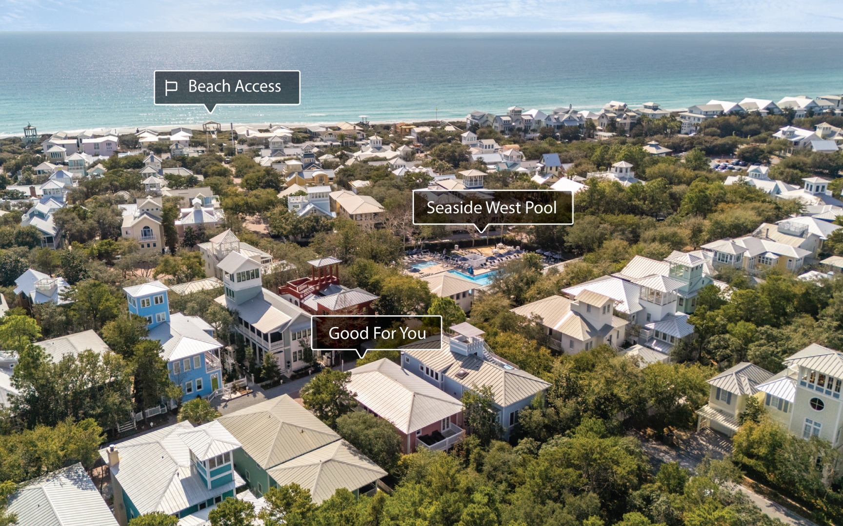 Aerial view of a charming beachside community with tree-lined streets leading to pristine white sand beaches and turquoise waters.