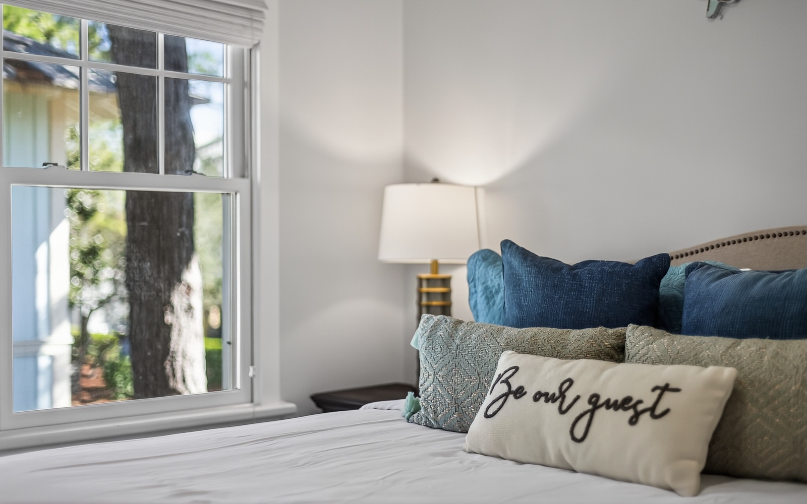 Sink into plush pillows and cozy textures in your beautifully appointed bedroom, where morning light streams through charming windows.
