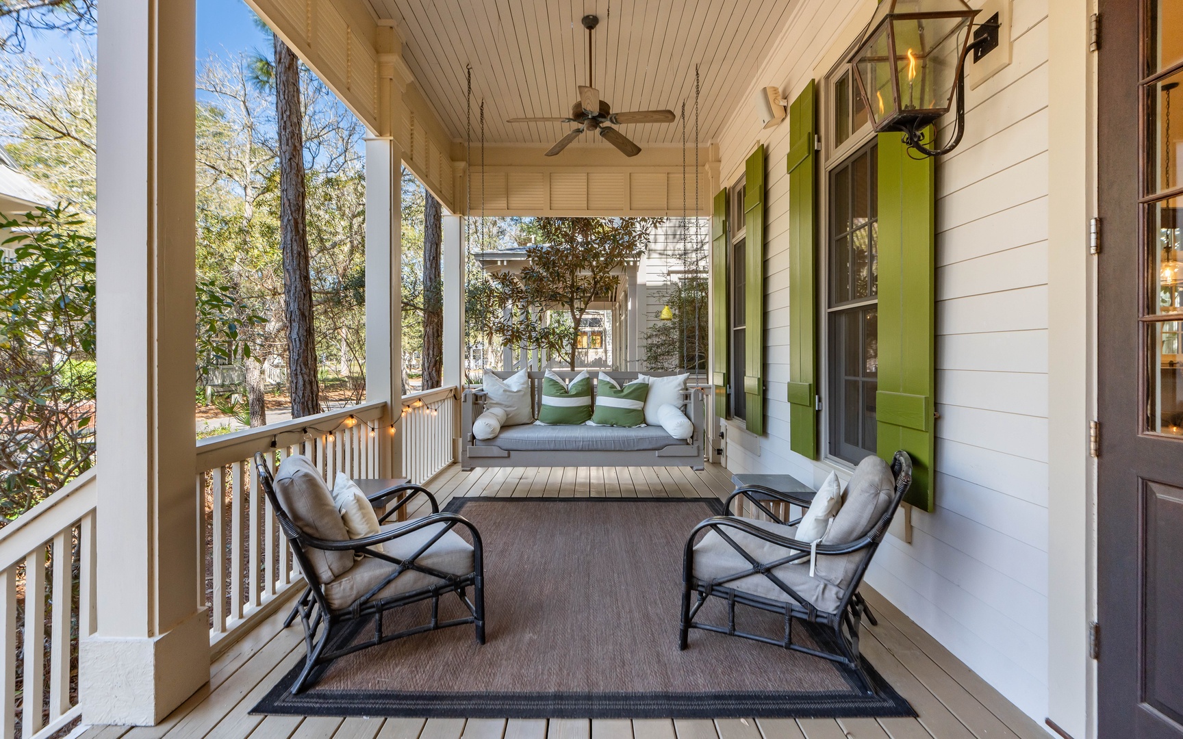 Unwind on your private covered porch with plush seating and swing bed, surrounded by mature trees for peaceful relaxation.