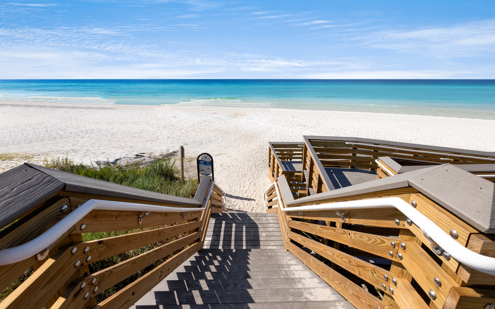 Wooden boardwalk provides direct beach access to pristine white sand and crystal-clear turquoise waters.