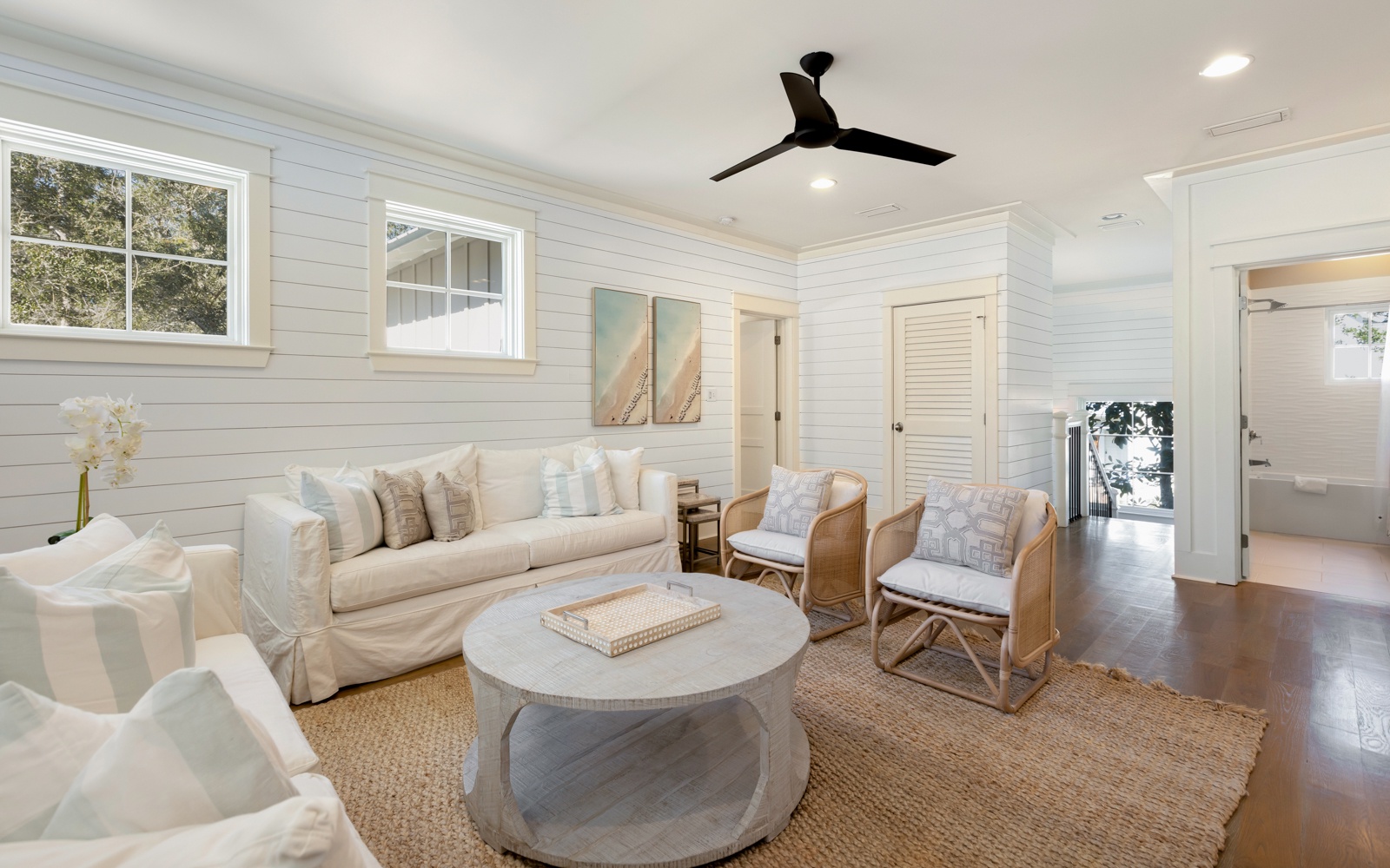 Unwind in your elegant living room featuring plush white seating, warm wood accents, and coastal charm perfect for peaceful evening conversations.