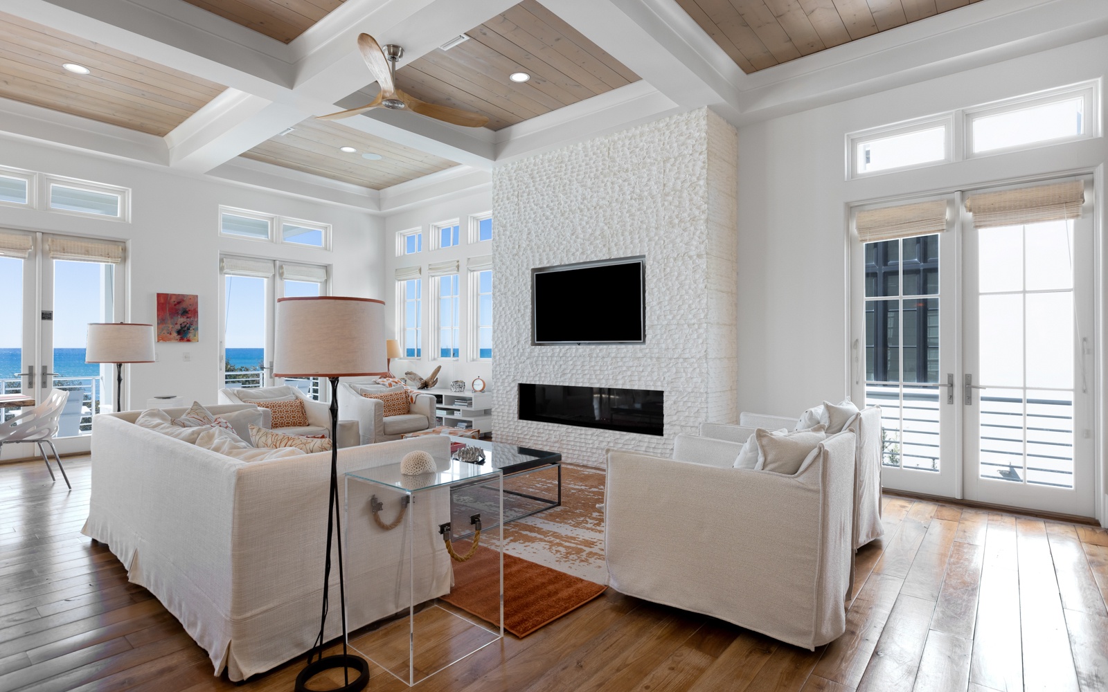 Unwind in your elegant living space with soaring coffered ceilings, cozy fireplace, and stunning ocean views through floor-to-ceiling windows.