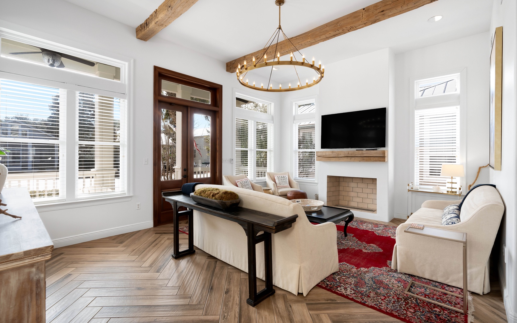 Unwind in your elegant living room featuring soaring wood beams, a cozy fireplace, and abundant natural light streaming through windows.