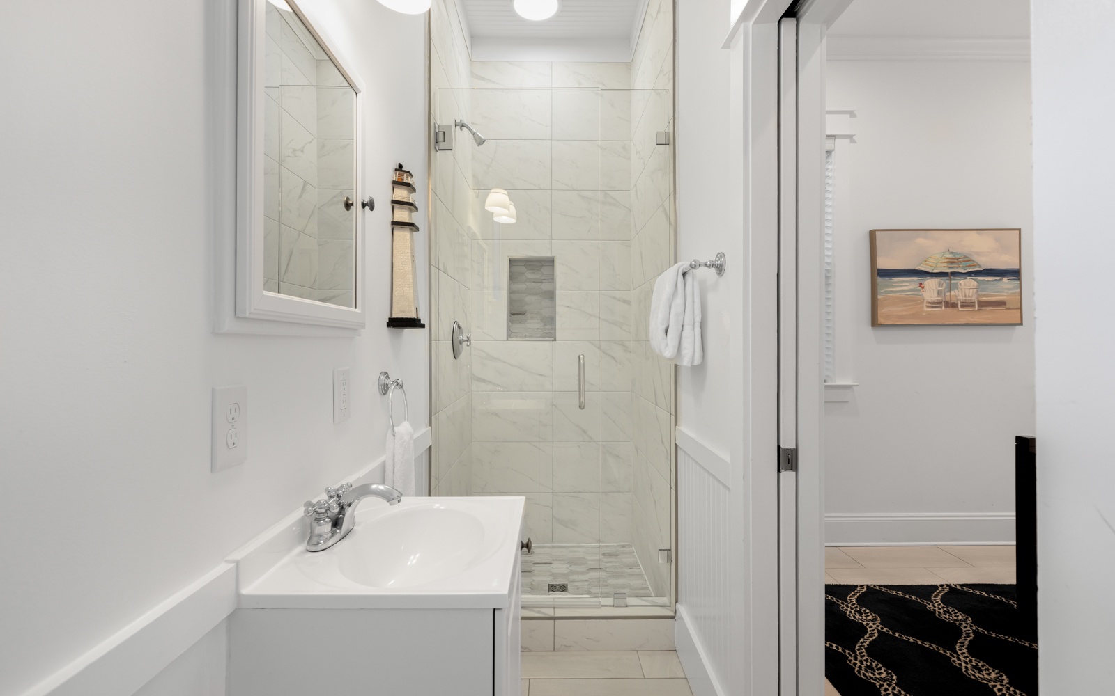 Step into your pristine bathroom with marble shower, fresh towels, and coastal artwork creating a spa-like retreat.