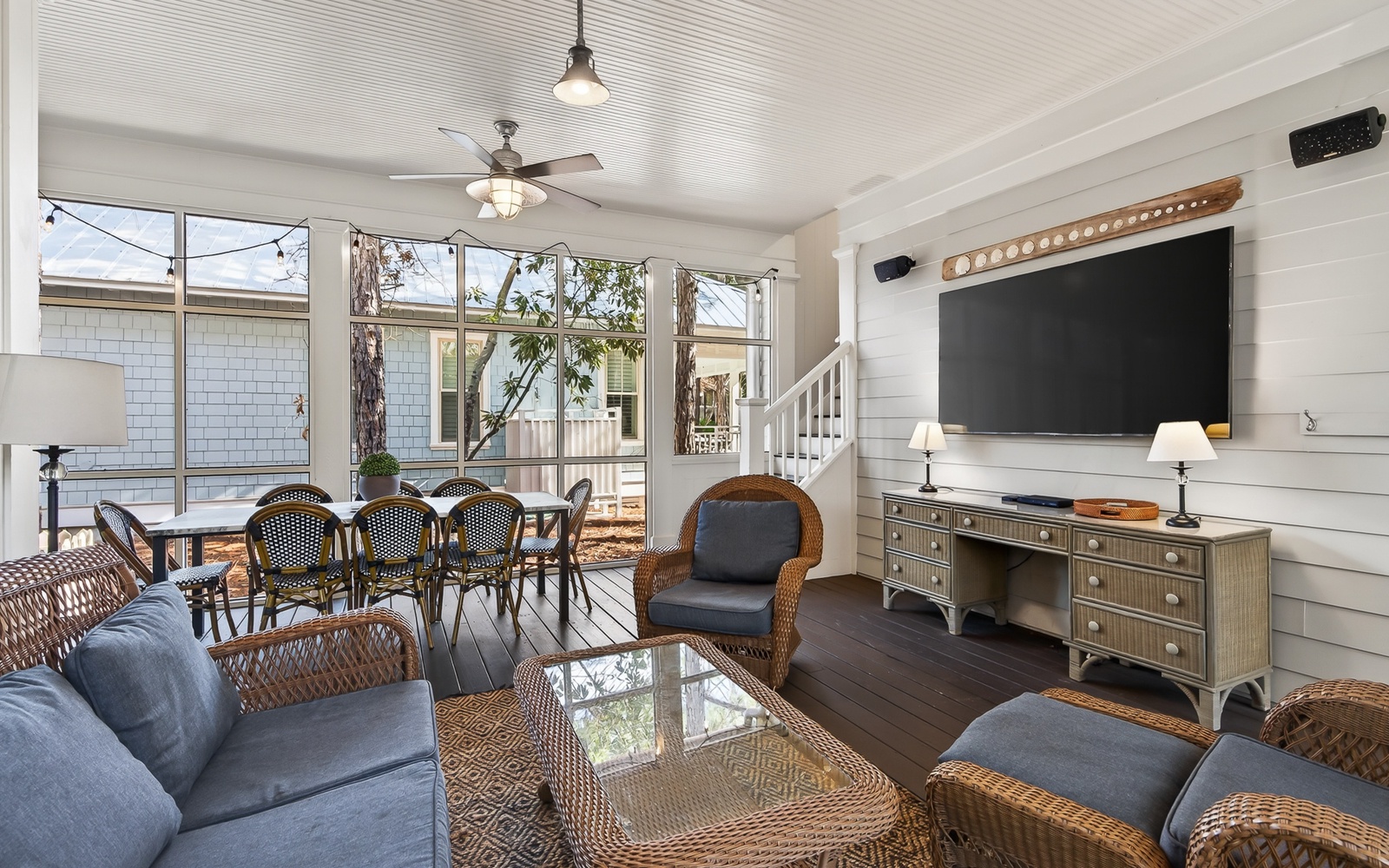 Relax in your coastal living room with wicker seating, ceiling fan, and large windows overlooking the charming neighborhood.