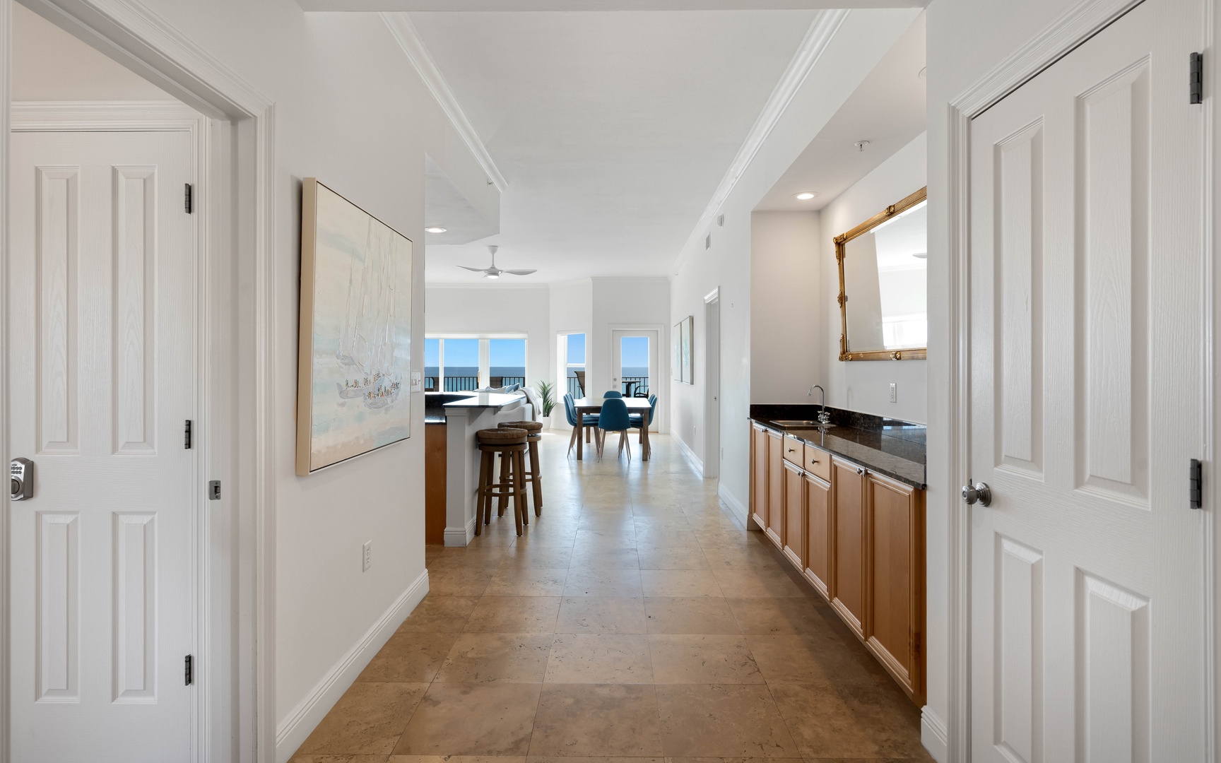 Step into your bright, elegant hallway featuring rich stone flooring and stunning ocean views ahead—perfect for memorable coastal getaways.