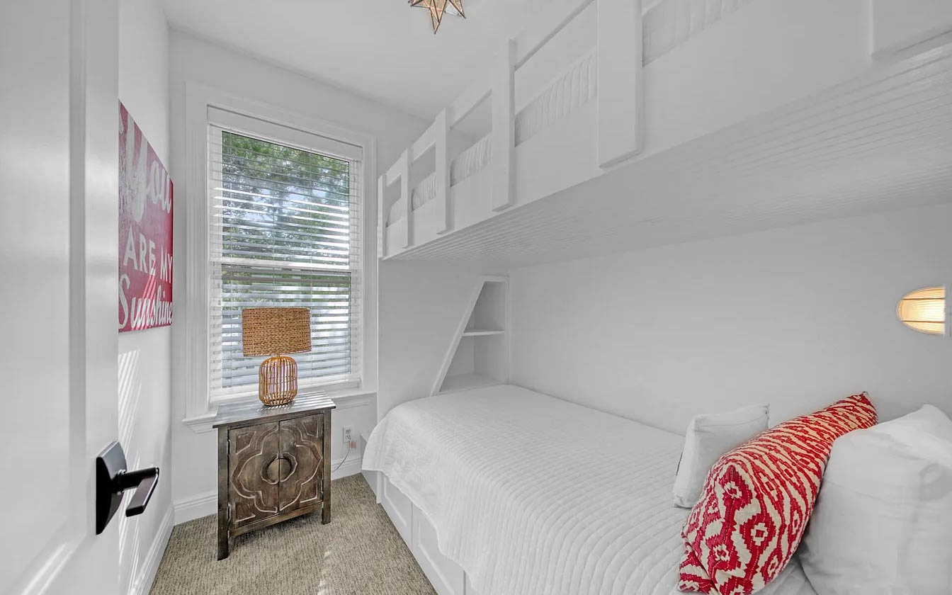 Your cozy bunk room features custom built-in beds with crisp white linens and cheerful red accents, perfect for restful nights.