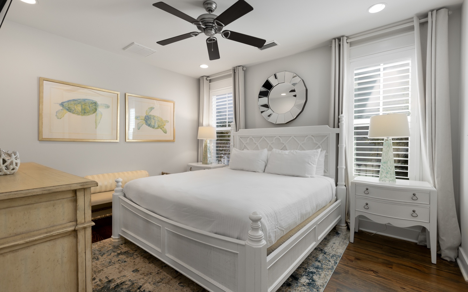 Rest peacefully in this elegant bedroom featuring a plush queen bed, calming sea turtle artwork, and gentle ceiling fan for your comfort.