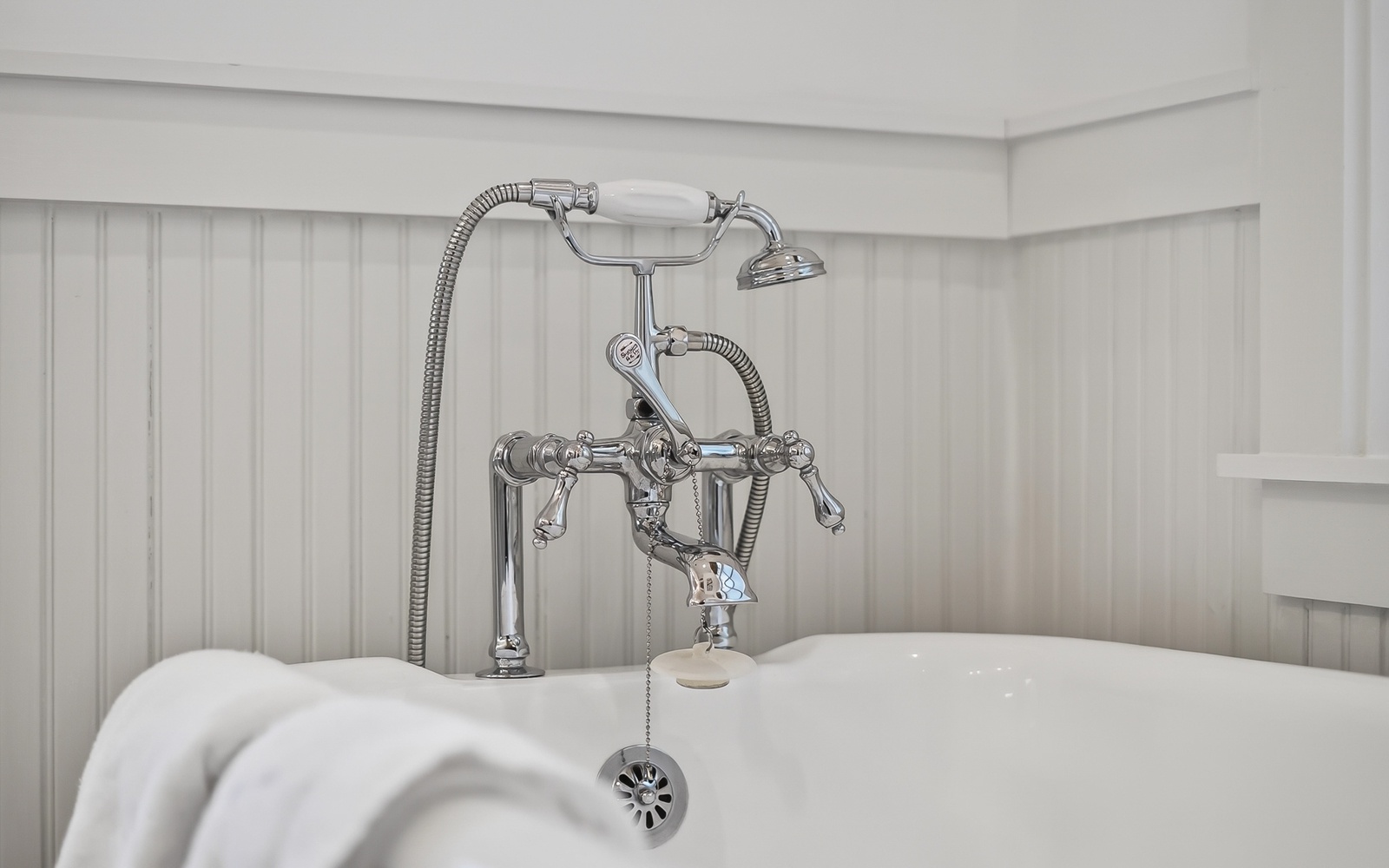 Sink into vintage luxury with this elegant clawfoot tub featuring polished chrome fixtures and classic wainscoting for your perfect soak.
