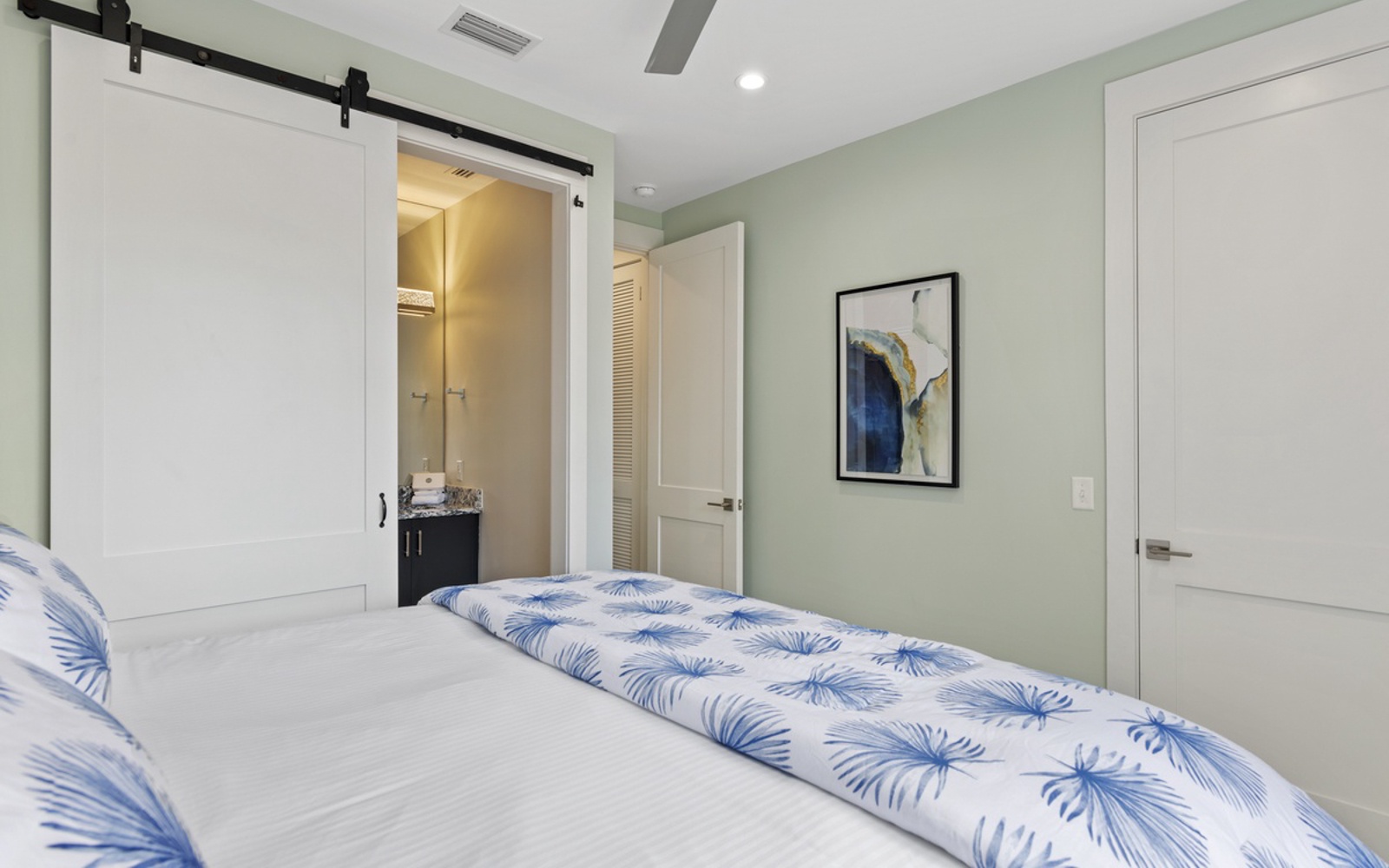 Unwind in your serene bedroom with soft palm-print linens and a unique sliding barn door leading to your private ensuite.